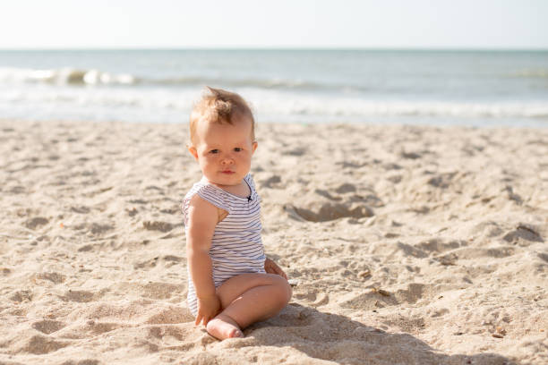 istock Small girl sitting on sand at beach 1314793411