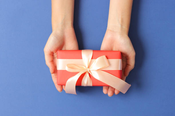 istock gift in female hands on a colored background top view. 1314793501