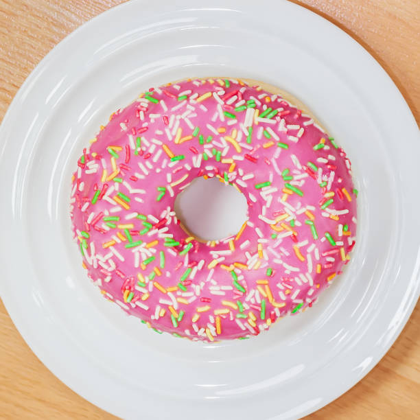 istock Delicious appetizing donut with pink icing on white plate, top view. 1314793588