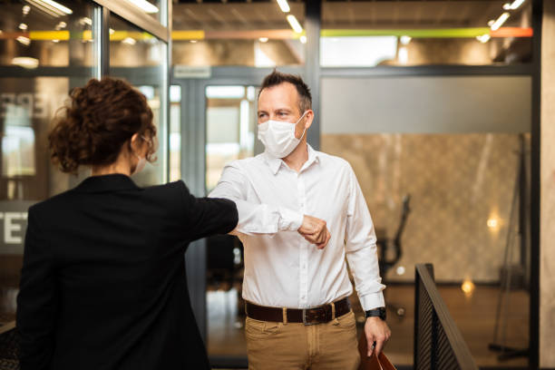istock Coworkers greeting with elbows while wearing protective face masks. 1314800202