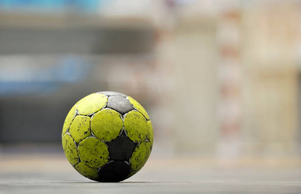 Handball ball on floor Yellow handball ball on floor, goal blurred in the background. handball stock pictures, royalty-free photos & images