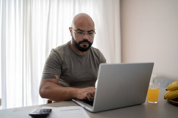 istock Mid adult man using laptop working or doing home finances 1314803305