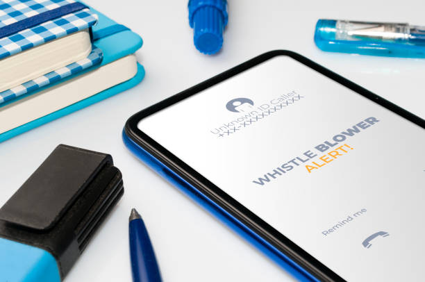 istock Whistleblowing concept: smartphone on white table show a whistle blower alert on an anonymous ID call 1314803931