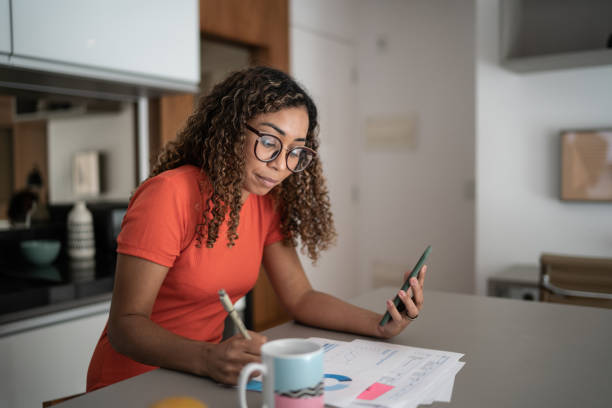 Woman doing home finances and using mobile phone at home