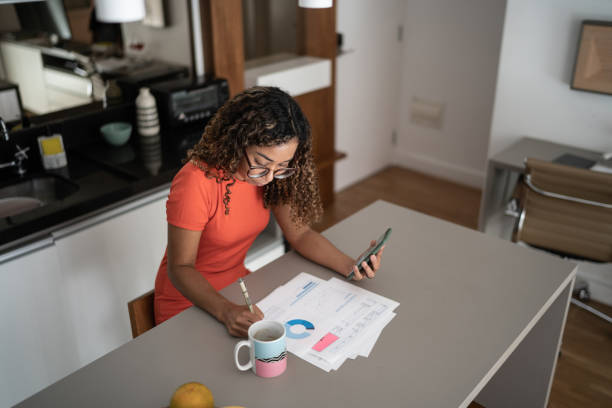 istock Woman doing home finances and using mobile phone at home 1314803950
