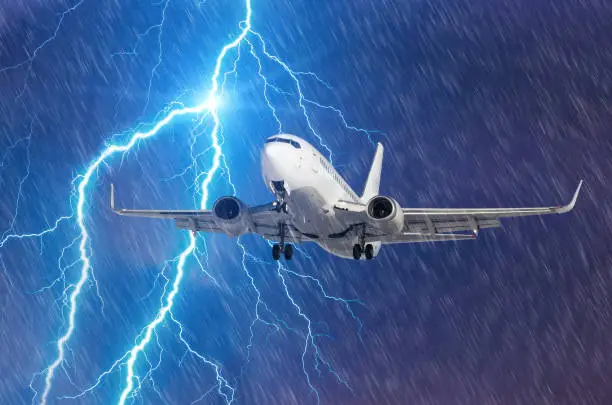 Photo of Lightning hits strike during a heavy downpour, behind a flying plane.