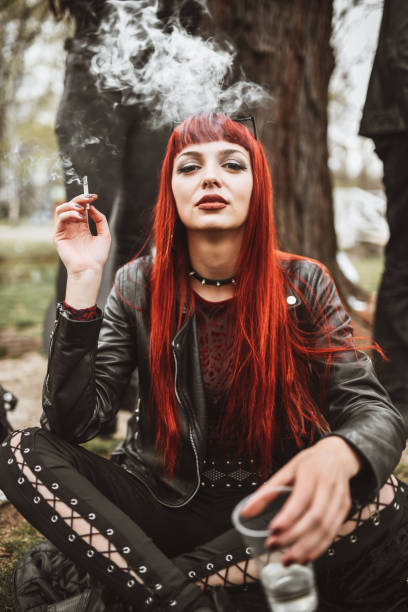 istock Beautiful Redhead Gothic Female Smoking Cigarettes And Drinking Wine In Park 1314806202