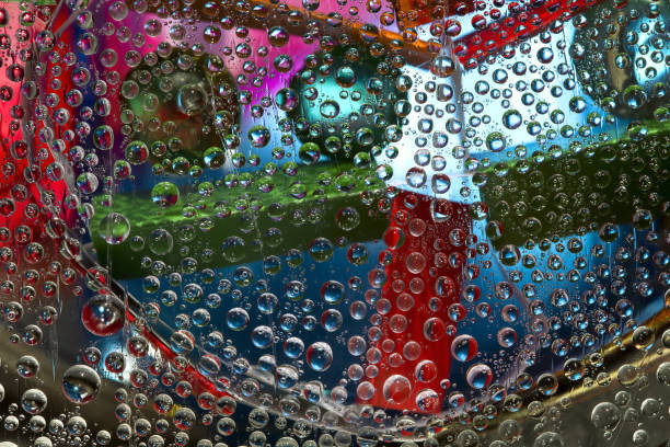 istock Translucent water droplets fall down against the blue-gold background with multicolored geometric figures. Abstract fantasy. 3D render. 1314806982