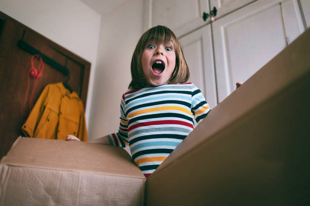自宅で配達ボックスを開く幸せな少年 - 子ども 驚く ストックフォトと画像