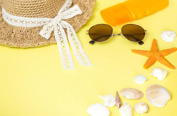istock Straw hat, glasses, sun cream and seashells lie on a yellow background 1314811808
