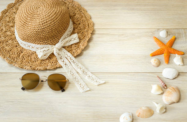 istock Hat, sunglasses and starfish with shells lie on a wooden surface. View from above 1314811831