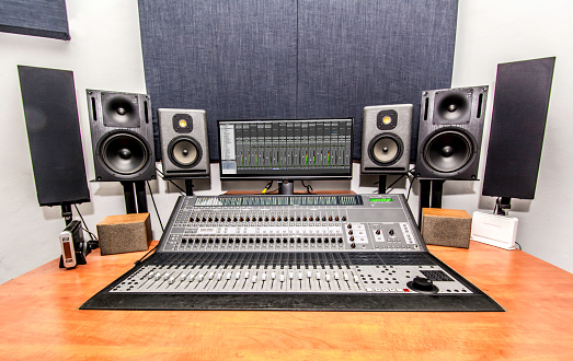The soundboard on a wooden table with sound boxes, microphones and a monitor