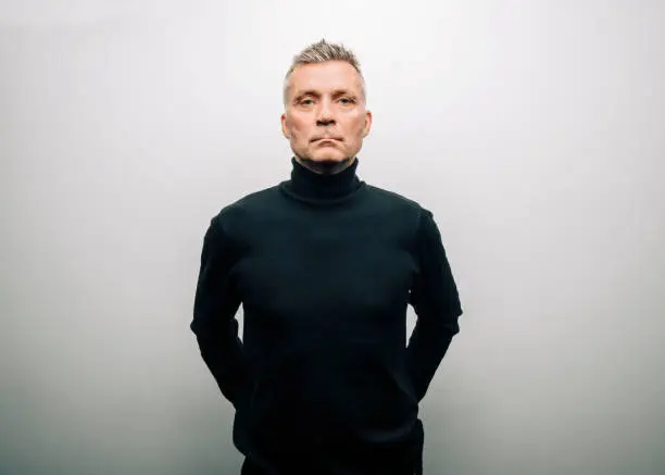 Senior man wearing turtle neck t-shirt. Confident male in casuals staring at camera against white background.