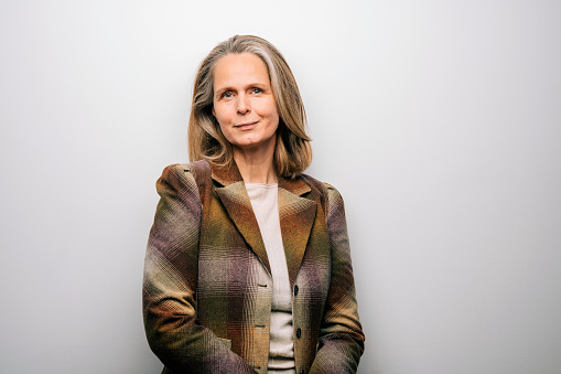 Portrait of senior woman wearing jacket staring at camera. Mature woman in jacket on white background looking confidently.