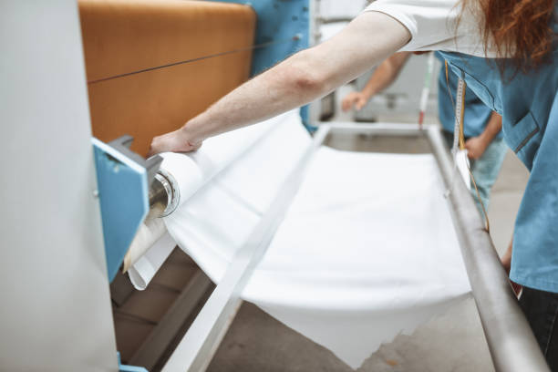 istock Workers In Textile Factory Putting Textile Materials On Print Roller 1314812199