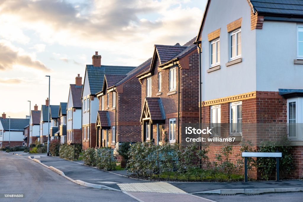 Houses in England with typical red bricks at sunset - Main street in a new estate with typical British houses on the side - Real estate and buildings concepts in UK House Stock Photo