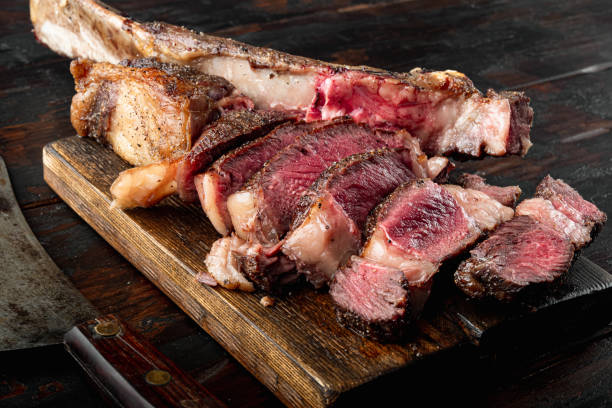 istock Grilled steak on the bone sliced, medium rare tomahawk cut, on wooden serving board, on old dark  wooden table background 1314816803