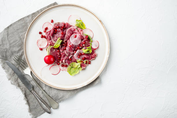 klasyczny carpaccio wołowy, z rzodkiewką i granatem, na talerzu, na białym kamiennym tle, widok z góry płaski leżał, z kopią miejsca na tekst - beef carpaccio zdjęcia i obrazy z banku zdjęć