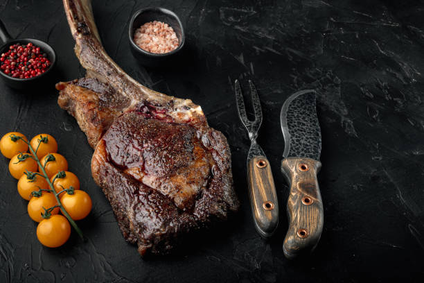 istock Beautifully seared tomahawk steak, medium rare , on black stone background, with copy space for text 1314817091