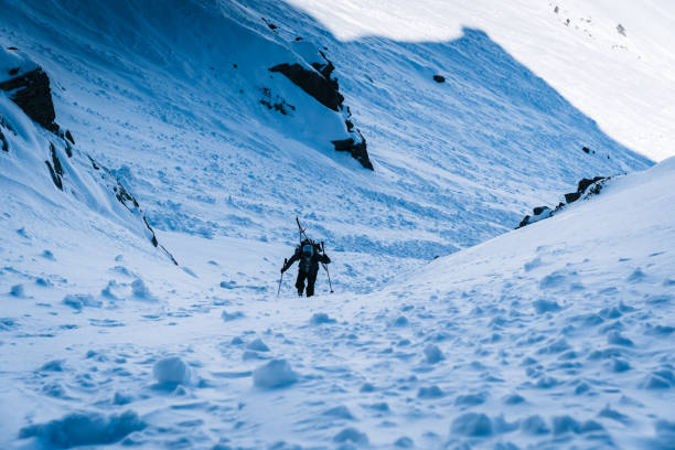 istock Ski mountaineer with splitboard climbs steep snow slope 1314818104