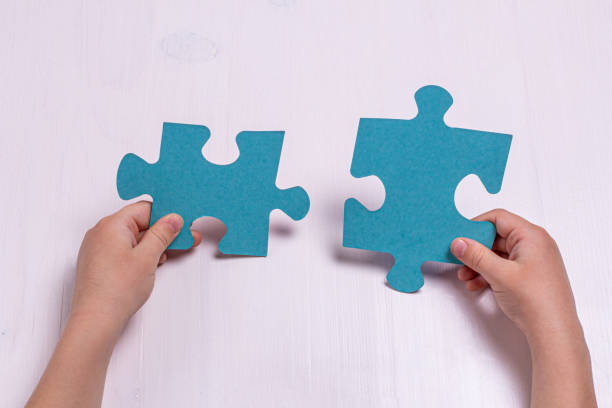 istock Children's hands hold two puzzle pieces on a light background. 1314823816
