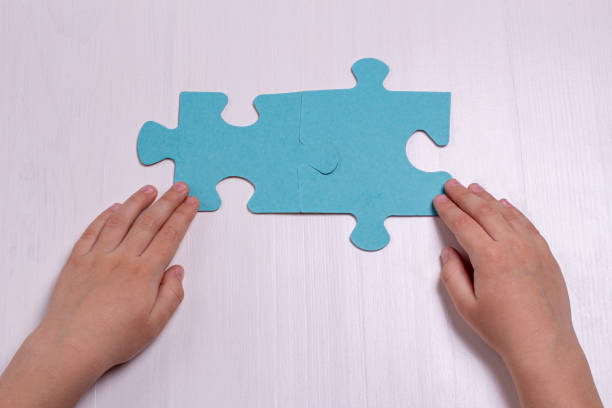 istock Children's hands hold two puzzle pieces on a light background. 1314824080