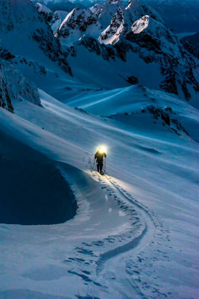 istock Ski mountaineer with headlamp climbs snowy mountain slope 1314825568