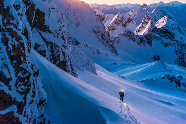 istock Ski mountaineer with headlamp climbs snowy mountain slope 1314825697