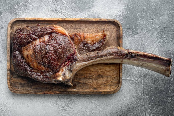istock Grilled black angus beef tomahawk steak on bone, on wooden serving board, on gray stone background, top view flat lay 1314827276