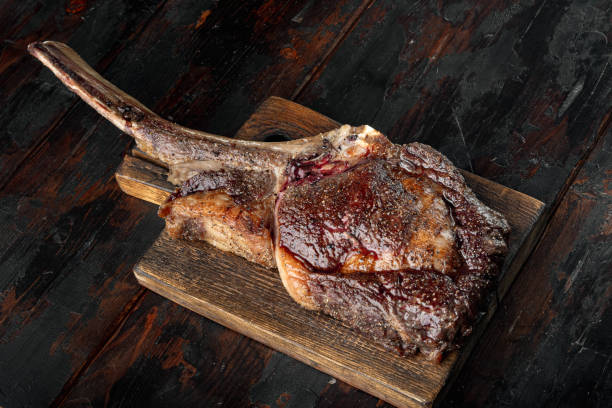 tomahawk bife de carne grelhado com especiarias, em tábua de madeira, em fundo de mesa de madeira escura velha - cutlet meat steak veal - fotografias e filmes do acervo