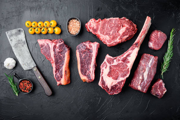 various cuts of marbled beef meat and dry aged steaks, tomahawk, t bone, club steak, rib eye and tenderloin cuts, on black stone background, top view flat lay, with copy space for text - veal t bone steak raw steak imagens e fotografias de stock