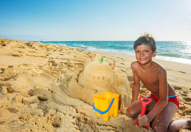 istock Handsome boy build sand castle on the sea beach 1314828558