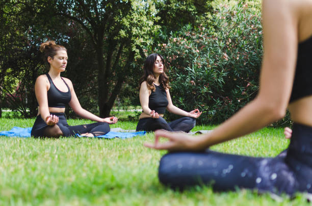 istock Three young women meditating in the park 1314828740