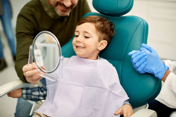 istock Cute boy looking his teeth in a mirror after dental procedure at dentist's office. 1314828793