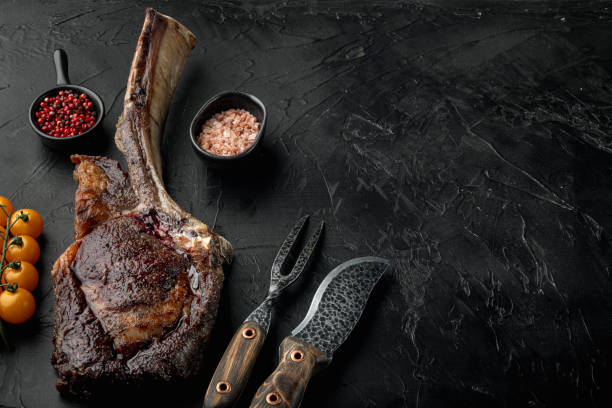 Grilled tomahawk beef steak, on black stone background, with copy space for text