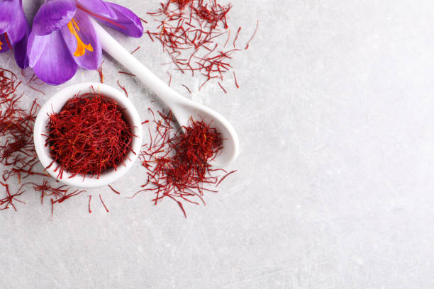 Dried saffron and crocus flowers on grey table, flat lay. Space for text