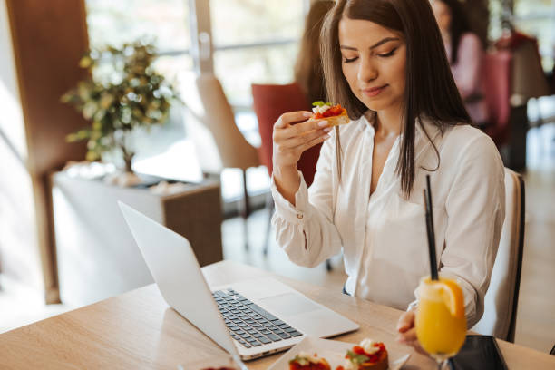 istock Young woman working on laptop while having breakfast in restaurant 1314833515