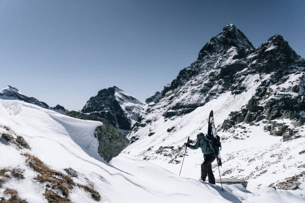 Ski mountaineer with splitboard climbs up mountain