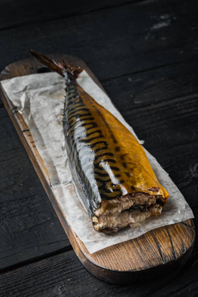 istock Appetizing smoked fish, on black wooden table background 1314834914