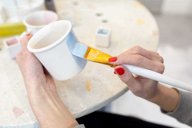 istock Women's hands paint a clay mug in blue. Learning new skills, improving skills, hobbies. Ceramic art concept. Selective focus 1314839429