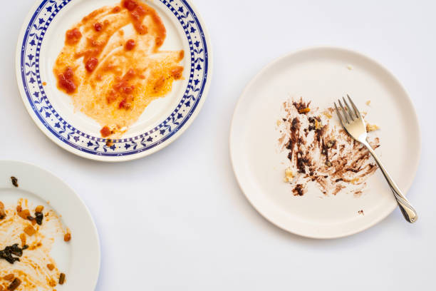 istock Dirty plates with food leftovers and fork on white background, top view 1314842744