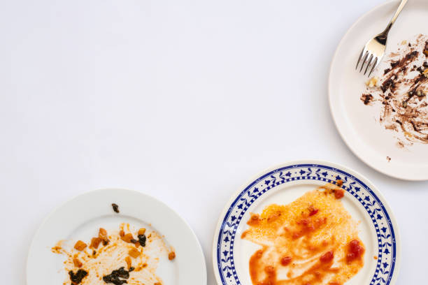 istock Dirty plates with food leftovers and fork on white background, top view 1314842826