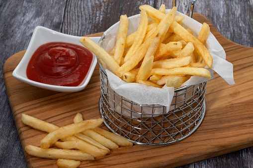 A metal basket of thin cut French fries