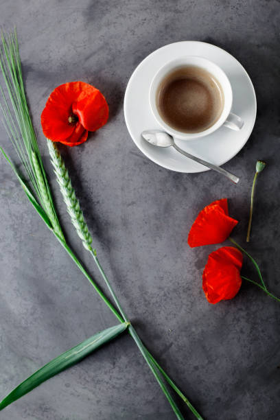 Cup of black coffee set with wild flowers - poppies, on grey grunge background