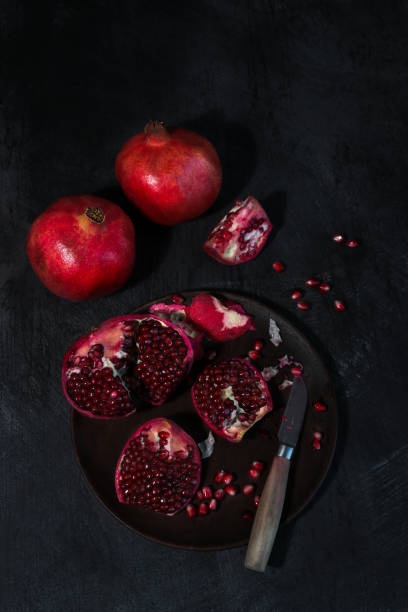 istock Pomegranate Fruits cut open with seeds on dark background 1314848532