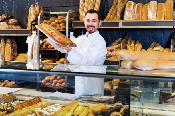 istock Man baker showing warm tasty bun in bakery 1314851853