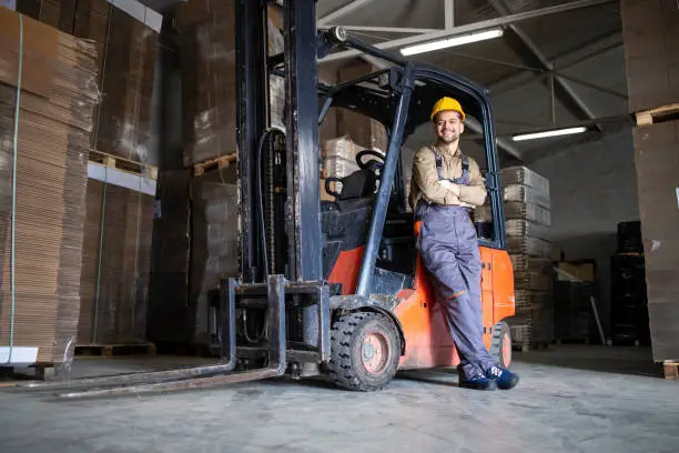 Photo of Experienced forklift driver in warehouse storage room.