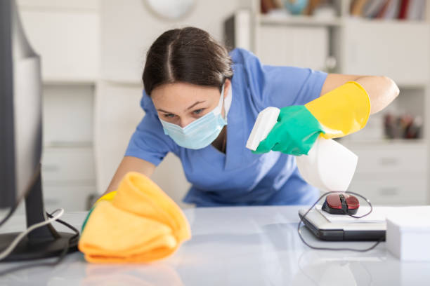 istock Woman in protective mask wipes dust from table in office 1314853998