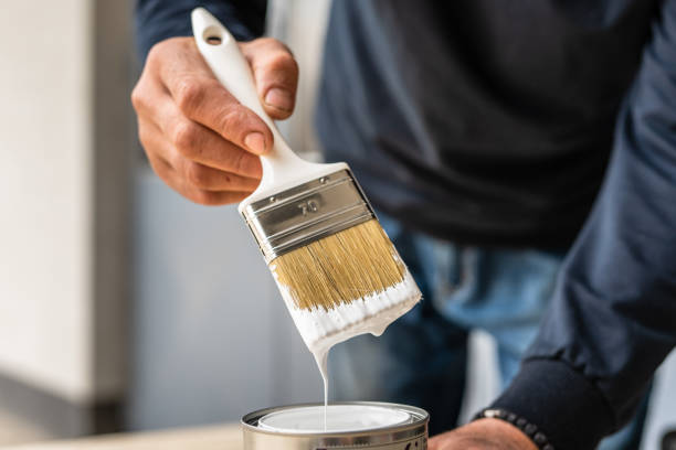 Close up on white paint brush in the hand of unknown man hobby painting and renovation repairing concept stock photo