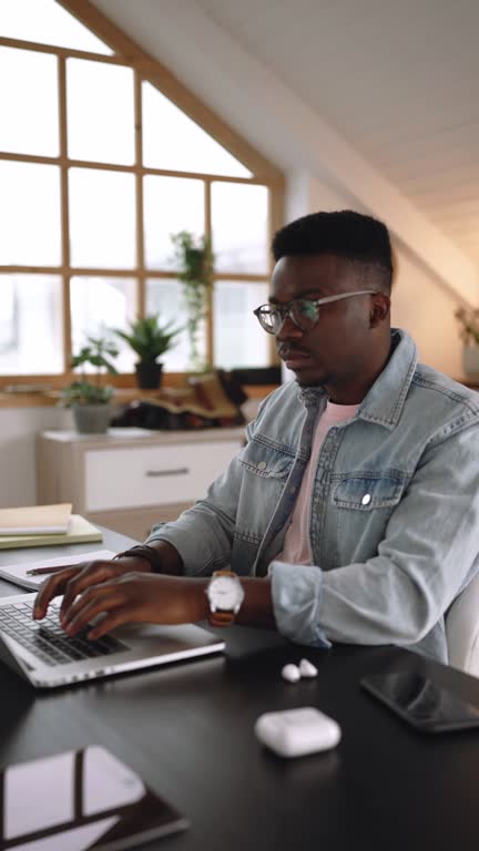 Young casually clothed businessman working from the comfort of his home office setup